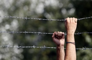 A man holds the fence and looks over at the Horgos border crossing into Hungary, near Horgos, Serbia, Wednesday, Sept. 16, 2015. Small groups of migrants continued to sneak into Hungary on Wednesday, a day after the country sealed its border with Serbia and began arresting people trying to breach the razor-wire barrier, while a first group arrived in Croatia seeking another way into the European Union. (AP Photo/Darko Vojinovic)