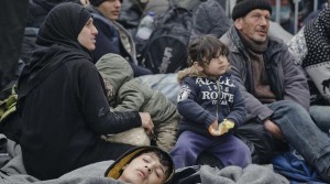 Migrants wait by the border gate between Greece and Macedonia at the northern Greek border station of Idomeni, Monday, March 7, 2016. Greek police officials say Macedonian authorities have imposed further restrictions on refugees trying to cross the border, saying only those from cities they consider to be at war can enter as up to 14,000 people are trapped in Idomeni, while another 6,000-7,000 are being housed in refugee camps around the region.(AP Photo/Vadim Ghirda)