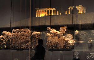 Fragments of the Parthenon frieze are reflected in the windows of the Parthenon hall at the new Acropolis museum during its official opening on June 20, 2009 in Athens as the Acropolis stands in the background. Designed by celebrated Franco-Swiss architect Bernard Tschumi, the three-level building set out over a total area of 25,000 square metres (270,000 square feet) will display more than 350 artefacts and sculptures that were previously held in a small museum atop the Acropolis. AFP PHOTO / LOUISA GOULIAMAKI