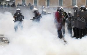 Riot police surrounded by teargas in front of the parliament in Athens