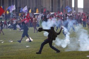 An anti-government demonstrator throws back a tear gas canister during a clash with riot policemen during a protest against a constitutional amendment, known as PEC 55, that limits public spending, in front of Brazil's National Congress in Brasilia, Brazil November 29, 2016. REUTERS/Adriano Machado