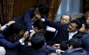 Lawmakers crowd around Yoshitada Konoike, chairman of the upper house special committee on security, as Masahisa Sato (R) of Japan's ruling Liberal Democratic Party's fist lands on opposition Democratic Party of Japan lawmaker Hiroyuki Konishi (top) during a vote at an upper house special committee session on security-related legislation at the parliament in Tokyo, Japan, September 17, 2015. A panel in Japan's upper house on Thursday approved legislation for a security policy shift that would allow troops to fight abroad for the first time since World War Two, a ruling party lawmaker said. REUTERS/Yuya Shino