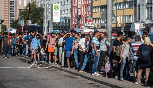 epa04907466 Migrants wait for transportation to one of the migrant reception centres, at Munich's central train station, in Munich, Germany, 01 September 2015. Hungarian police on 01 September 2015 closed the main train station in Budapest from where scores of migrants were hoping to travel to Western Europe. Hundreds boarded trains to Austria and Germany. Austrian police at the Vienna station and German police in Rosenheim, on the border with Austria, apparently made no effort to block or register any refugees.  EPA/NICOLAS ARMER