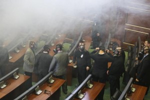 Kosovo parliament security staff wearing gas mask as opposition lawmakers release a tear gas canister disrupting a parliamentary session in Kosovo capital Pristina on Friday Feb. 19, 2016. Kosovo opposition again has used tear gas inside the Parliament disrupting its session, a repeated use of violent methods over the last five months to convince the government renounces its deals with Serbia and Montenegro. The opposition coalition has given the government an ultimatum until Feb. 27, to resign and call new elections in Kosovo. (AP Photo/Visar Kryeziu)