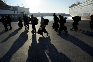 Refugees and migrants walk after disembarking from the passenger ferry Eleftherios Venizelos from the island of Lesbos at the port of Piraeus, near Athens, Greece, December 26, 2015. REUTERS/Michalis Karagiannis