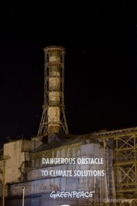 Greenpeace activists project the anti nuclear message "Dangerous Obstacle To Climate Solutions" onto the sarcophagus of the Chernobyl Nuclear Power Plant. The sarcophagus was built around the plant's stricken reactor using 7,000 tonnes of steel and 410,000 cubic meters of concrete. Now, 23 years after the devastating accident that claimed lives of tens of thousands, the nuclear industry is trying to survive by exploiting the climate crisis.