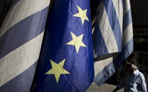 A man walks past a European and Greek flags in central Athens, on Tuesday, June 30, 2015. The European part of its international bailout expiring Tuesday and with it, any possible access to the remaining rescue loans it contains. As a result, the government is unlikely to repay a roughly 1.6 billion-euro ($1.87 billion) debt to the International Monetary Fund due Tuesday too. (AP Photo/Petros Giannakouris)