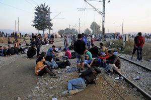 Refugees and migrants rest on railway tracks as they wait to cross the borders of Greece with Macedonia, near the village of Idomeni